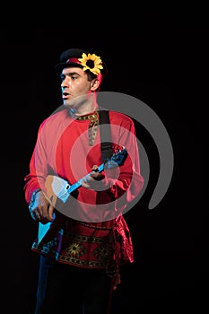 Artist musician A brunette man in a red folk shirt plays a balalaika