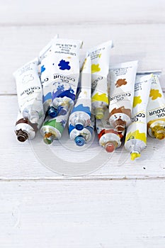 Artist oil paint tubes in various colours on white wood.  Art and craft supplies