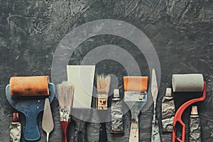 Artist paint brushes, brush rollers, palette knifes, paint tubes closeup on gray concrete background. photo