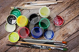 Artist paint brushes and jars with acrylic paint on wooden background.Painting hobby background. Paintings art concept.