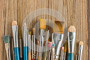 Artist paint brushes over rustic wooden texture