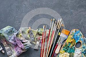 Artist paint brushes, palette, palette knifes, paint tubes on gray concrete background