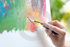 Artist painting on canvas with spatula