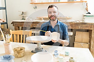 Artist Painting Earthenware With Paintbrush In Pottery Workshop