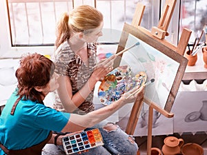 Artist painting easel in studio. Authentic grandmother and kids.