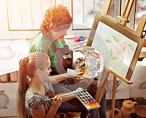 Artist painting easel in studio. Authentic grandmother and kids.