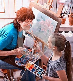 Artist painting easel in studio. Authentic grandmother and kids.