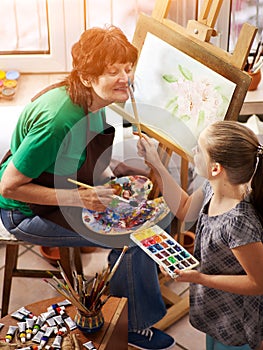 Artist painting easel in studio. Authentic grandmother and kids.