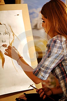 Artist painting on easel in studio. Girl paints portrait of woman with brush.