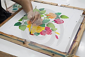 Artist painting flower on fabric.