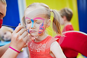 Artist painting little preschooler girl like butterfly. Creative activities for kids