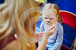 Artist painting little preschooler girl like cat. Creative activities for kids