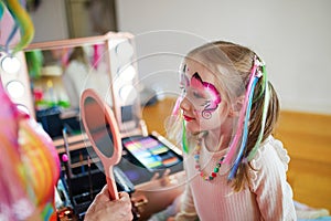 Artist painting little preschooler girl like unicorn on a birthday party photo