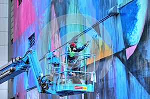 Artist painting mural on building in Sacramento