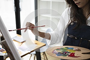 Artist painting picture with watercolor on canvas at workplace.