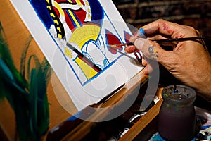 An artist painting a Queen of Hearts playing card on a canvas in their studio