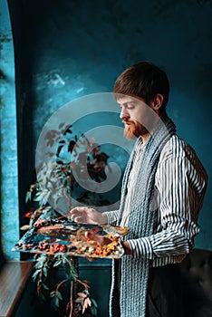 Artist with palette and brush in front of window