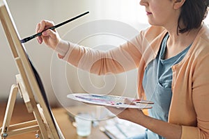 Artist with palette and brush painting at studio