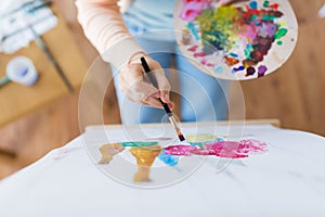 Artist with palette and brush painting at studio