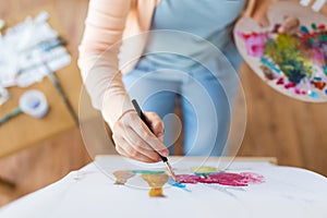 Artist with palette and brush painting at studio