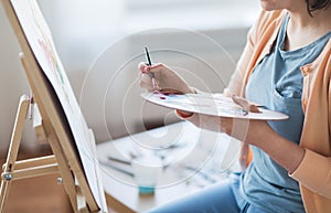 Artist with palette and brush painting at studio