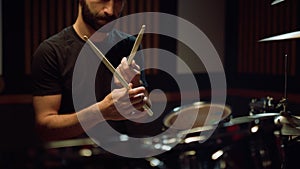 Artist preparing to concert in hall. Musician hitting drumsticks in studio.