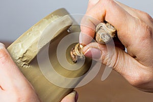 Artist pressing seal to ceramic pot. Potter printing stamp with trademark