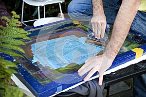 Artist pulling squeegee across silk screen.