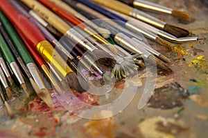 An artist`s brush on the palette, artists brushes and oil paints on wooden palette