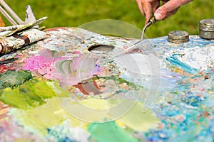 Artist's hand working with paletteknife outdoors