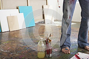 Artist's Legs By Brushes And Paint Thinner In Studio photo
