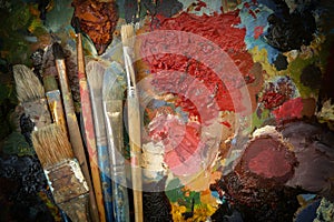 Artist`s old real brushes on a dark contrasting colorful palette. top view. copy space