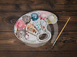 An artist`s palette and a brush on a wooden table. Flat lay