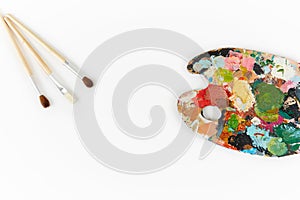 Artist`s palette and brushes with different colors isolated on a white background