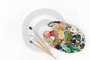 Artist`s palette and brushes with different colors isolated on a white background