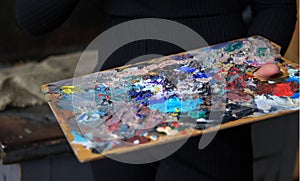 Artist`s palette, close-up. Selective focus on the foreground. The artist`s palette with paints, the artist interferes