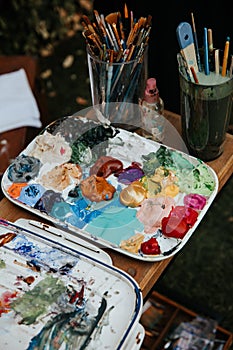 Artist's palette with colorful acrylic and oil paints, paint brushes and pencils