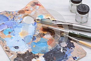 Artist`s palette with colorful oil paint strokes and paintbrushe