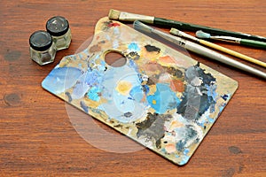 Artist`s palette with colorful oil paint strokes and paintbrushe