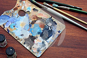 Artist`s palette with colorful oil paint strokes and paintbrushe