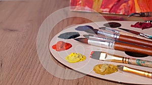 Artist`s palette with many colorful paints and brushes on wooden table, closeup. Space for text