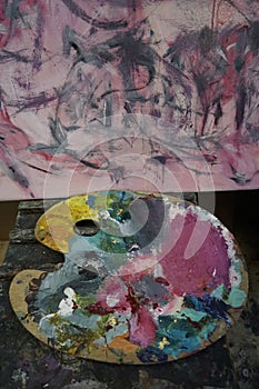 Artist`s palette with oil paints and brushes, soft focus. Artistic paintbrushes, paints and palette knife on an old wooden palett