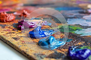 Artist`s palette with oil paints of a cold spectrum