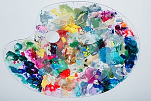 The artist`s palette stained with paint. On a white background, nobody