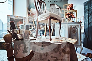 Artist`s workshop with necessary eguipment  like paint, brushes, frames, flowers, table,  chair and cupboard.