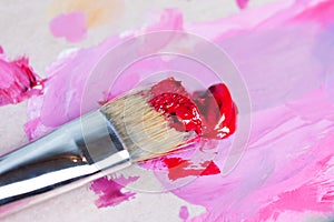 The artist squeezed the paint onto the palette and mixes the pink paint with a synthetic brush