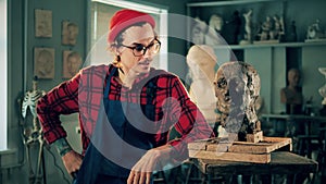 An artist is standing next to a clay head in the studio. Art concept, creative studio interior.