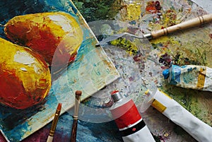 Artist studio with oil paints, brushes and colorful picture