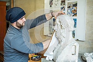 Artist/teacher cleaning sculptures for study with a piece of cloth - side view