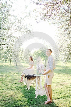 Artist with watercolor painting of bride in wedding dress outdoors